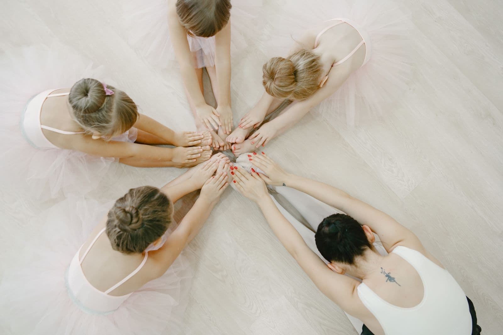 Overhead view of young ballet students in a circle on a studio floor, hands joined in the middle