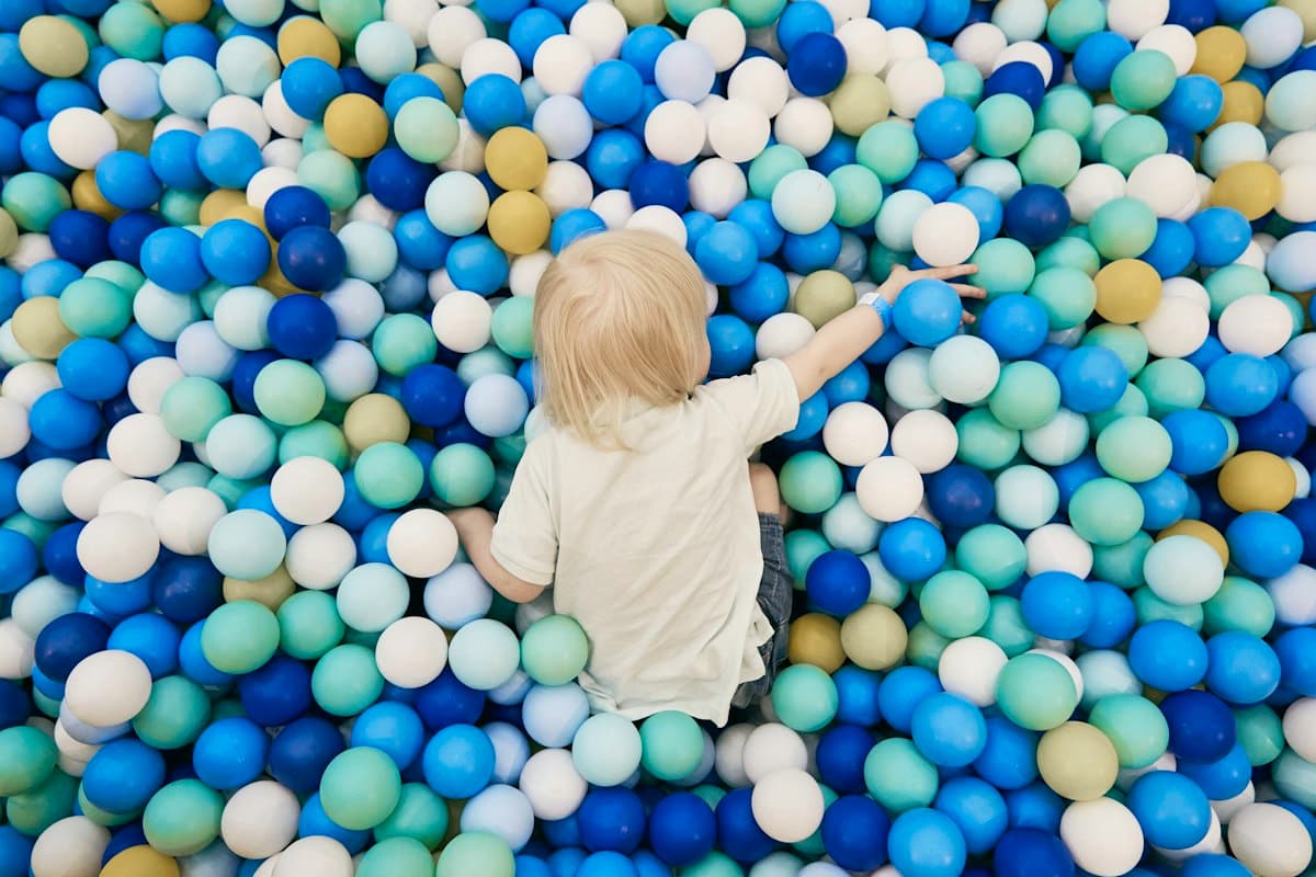 A small child sitting in a ball pit