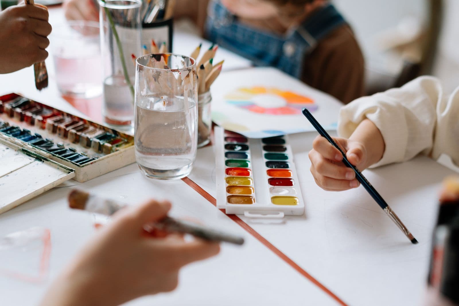 Children's hands painting with watercolours at a class table