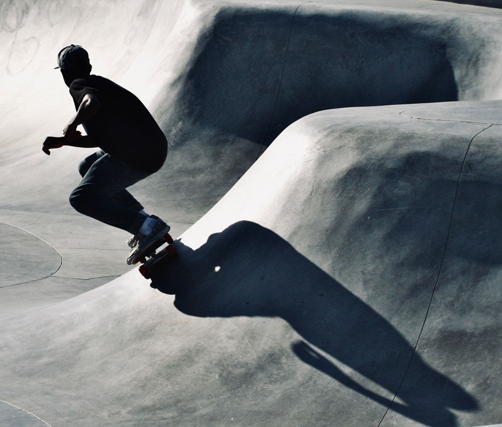 A skateboarder in silhouette riding a curved concrete skate bowl