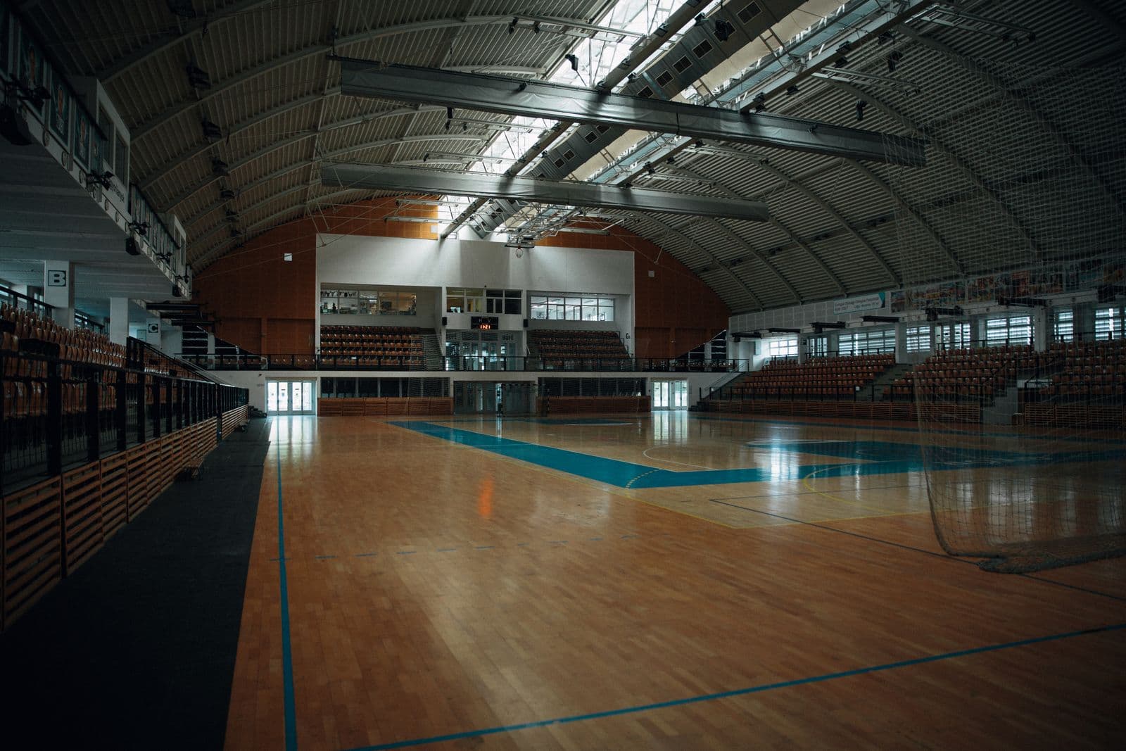 An empty indoor sports arena with a wooden court and bleachers